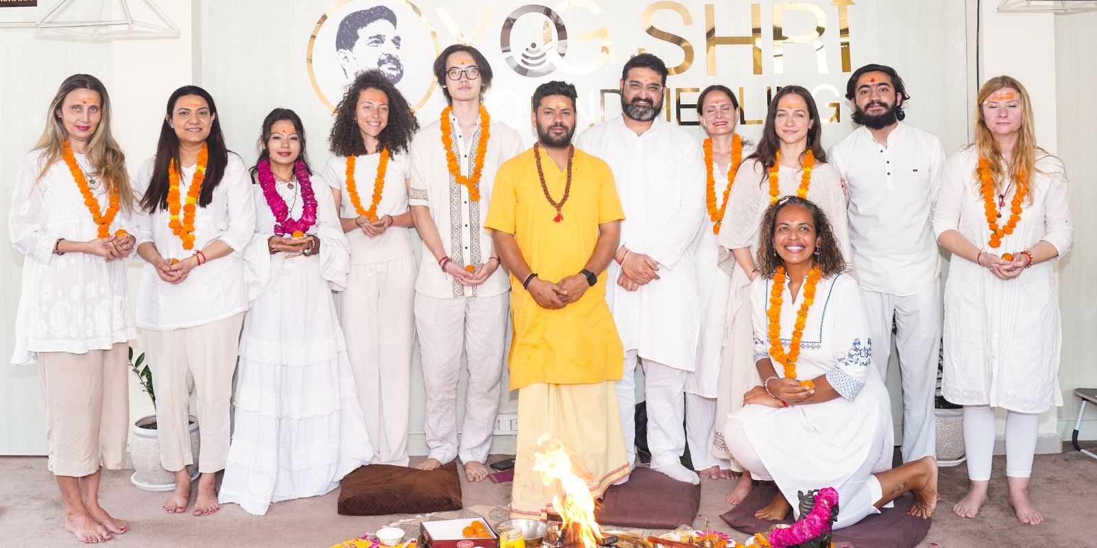 Group photo of Reiki healing practitioners and students dressed in white, adorned with marigold garlands, standing together after a spiritual healing ceremony at Yogshri Healing Center.